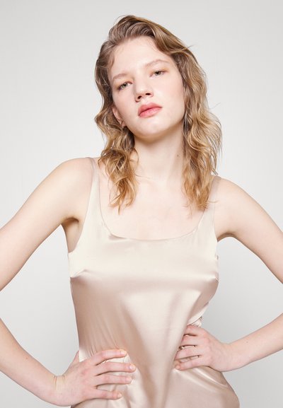 Σατέν καμεΐ σε ανοιχτό μπεζ με τετράγωνη λαιμόκοψη, ρυθμιζόμενους λεπτούς ώμους και απαλό υφή, στενό στη μέση.