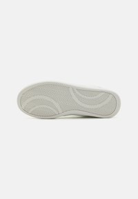 Suela de zapatilla blanca con una suela de goma texturizada que presenta un patrón de espiga y bordes suaves. Sin marcas ni acentos visibles.