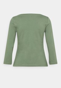 Vaaleanoliivi vihreä pitkähihaisempi tiukka paita, pyöreällä kaula-aukolla, kuvattuna takaa valkoista taustaa vasten.