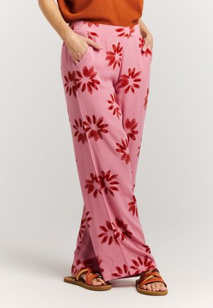Roze wijde broek met een bloemenpatroon in het rood. Gemaakt van lichtgewicht stof, met zijzakken en een ontspannen pasvorm, gecombineerd met sandalen.