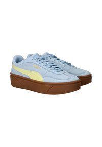 Blauwe suède sneakers met gele accenten en een dikke bruine plateauzool. Voorzien van een vetersluiting en PUMA-branding aan de zijkant.