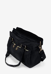 Bolso de mano negro de nailon con herrajes dorados, múltiples bolsillos con cremallera y correas dobles. Cuenta con un interior espacioso y abierto para una mejor organización.