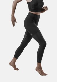 Zwart activewear set bestaande uit een aansluitende crop top en hoge taille legging, met textuur zijpanelen en een gladde algehele afwerking.