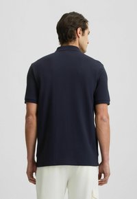 Polo shirt navy in tessuto morbido, con colletto classico e maniche corte. Presenta una texture liscia e un taglio pulito all'orlo.