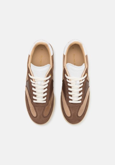 Zapatillas de ante y cuero marrón con acentos blancos, puntera redonda, cierre con cordones y detalles de panel texturizado. Suela de goma flexible.