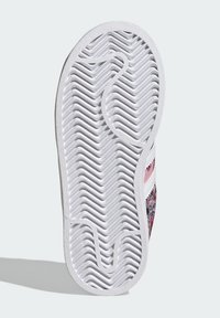 Podplat čevlja z belo gumijasto podlago in teksturiranim cik-cak vzorcem za oprijem. Cvetlični vzorec v rožnati in modri barvi na zgornjem delu.