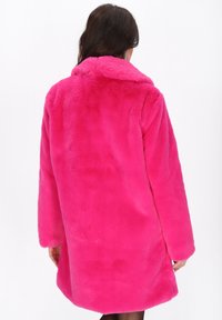 Faux fur jas in felroze, halflang met lange mouwen, een brede kraag en een zachte textuur. Heeft een rechte snit en geen zichtbare sluitingen.