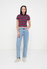 Stripete poloshirt i burgunder og marineblå med korte ermer, kombinert med lyseblå jeans med rette ben og beige sneakers.