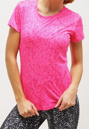 Maglietta sportiva rosa con un motivo astratto testurizzato. Maniche corte e scollatura rotonda. Indossata con leggings neri a fantasia.