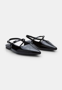 Ballerines slingback en cuir verni noir avec un bout pointu, présentant une sangle fine et un talon rectangulaire. Texture lisse avec finition brillante.