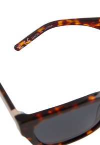 Branch des lunettes de soleil écaille avec les inscriptions "UK CA CE Made in China" sur fond blanc.