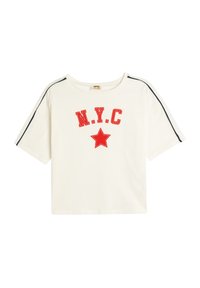 Hvid bomulds t-shirt med rød "N.Y.C." skrifttype og grafisk rød stjerne. Har sort kant langs skuldersømmene og korte ærmer.
