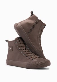 Zapatillas altas marrones de material liso, con cierre de cremallera, puntera redonda, suela de goma texturizada y diseño de cordones con ojales.