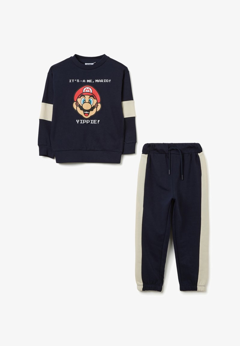Navyblauw kindertrainingspak met beige strepen op de mouwen en broek, voorzien van het gezicht van Mario en de tekst "It's-a me, Mario! Yippie!" op het sweatshirt.
