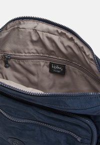 Navy blue bag with a textured exterior, a zippered main compartment, and a smaller zip pocket inside. Features a black brand label.