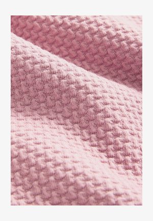 Textured pink fabric with a waffle pattern, displaying a soft, knitted texture. The surface has a slight sheen, creating dimension.
