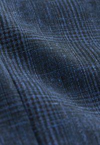 Tissu bleu foncé avec un motif à carreaux texturé, montrant en gros plan les détails des fils tissés et des plis subtils.