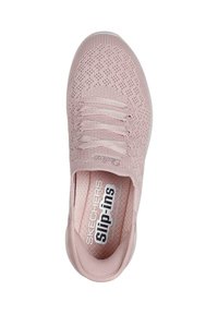 Zapato de punto rosa tipo slip-on con cordones elásticos, parte superior texturizada y plantilla acolchada. Presenta la marca Skechers en el lateral y en la plantilla.