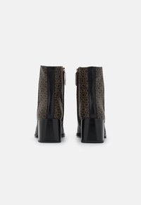 Czarne botki na obcasie z brązowymi panelami w wzory, wykonane z gładkiej skóry, z zamkiem błyskawicznym i srebrnymi ozdobami po bokach.