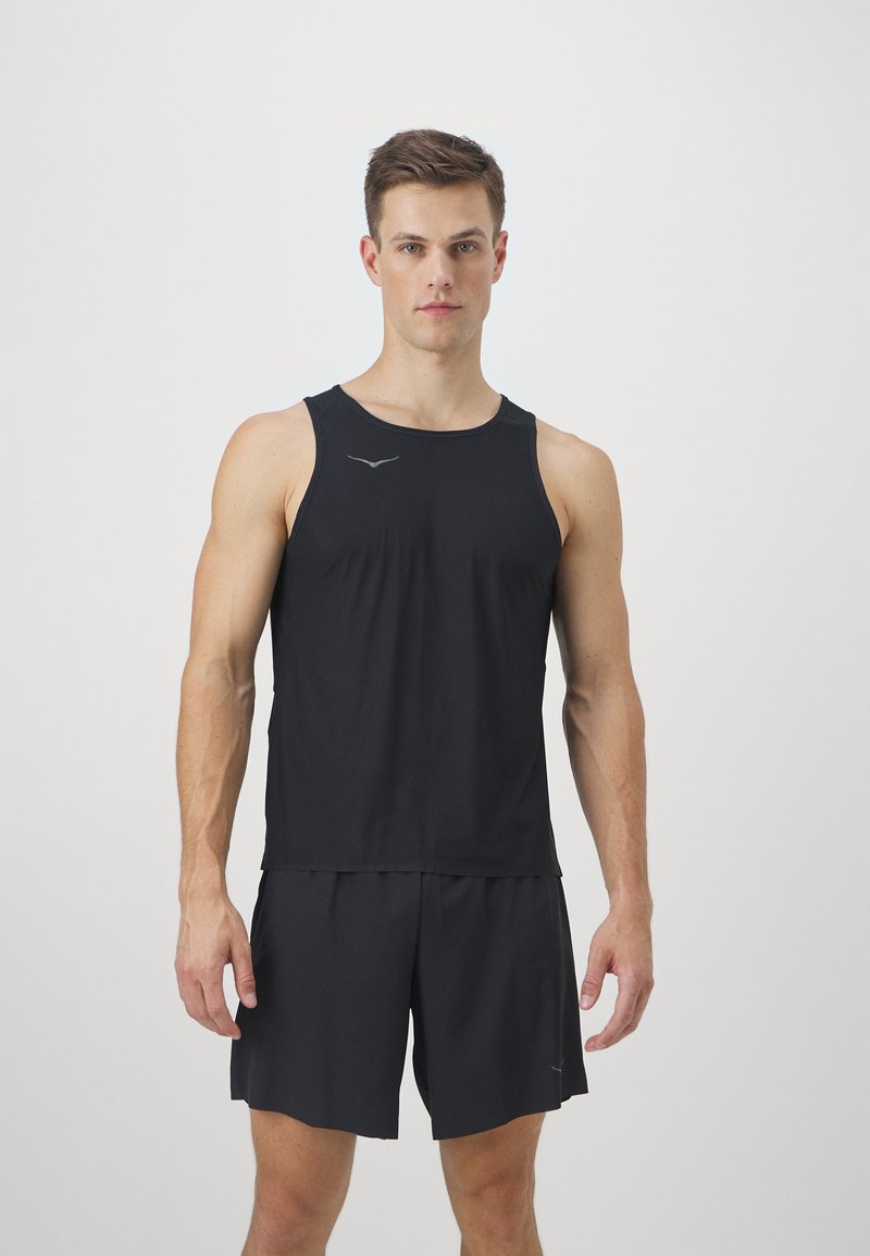 Svart atletisk tanktopp med rund hals og ermeløs design, kombinert med matchende svarte shorts. Har subtile logodetaljer.