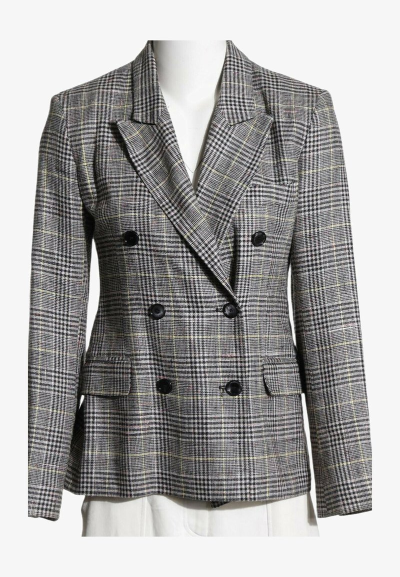 Blazer gris à carreaux croisé avec boutons noirs, revers crantés et poches à rabat sur un buste de mannequin blanc.