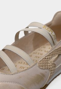 Μπεζ μπαλαρίνα με υφασμάτινα σχέδια φιδιού, ελαστικούς ιμάντες και χρυσό λογότυπο. Ομαλό υλικό με στρογγυλεμένο σχέδιο στην άκρη.