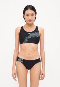 Zwart bikiniset met een sportieve bovenkant in een lichtblauw golfpatroon en bijpassende onderkant. Gemaakt van rekbare zwemstof.