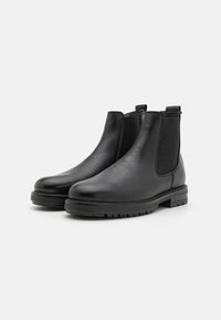Black leather Chelsea boots with a smooth finish, elastic side panels, pull tabs, and textured rubber soles for grip and durability.