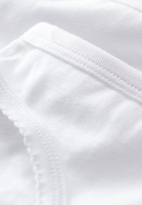 Tessuto bianco con texture liscia, caratterizzato da un bordo a coste e dettagli cuciti a contrasto lungo la cucitura.