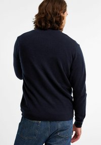 Navyblauwe gebreide trui met een ronde hals, geribbelde manchetten en zoom, die een gladde textuur en een ontspannen pasvorm toont. Achteraanzicht weergegeven.