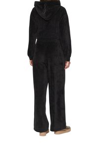 Zwart velours trainingspak met een cropped hoodie en wijde broekspijpen. Heeft een zachte textuur en een elastische tailleband voor comfort.