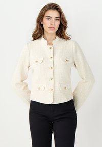 Elfenbeinfarbener Tweed-Blazer mit goldenen Knöpfen, ausgestattet mit einem Stehkragen und zwei Fronttaschen. Strukturierte Passform mit langen Ärmeln.