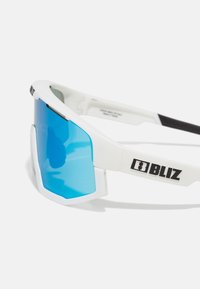 Ochelari de soare sportivi albi cu lentile nuanțate în albastru și accente negre. Design cu ramă unghiulară mare, cu marcaj pe lateral. Material plastic ușor.