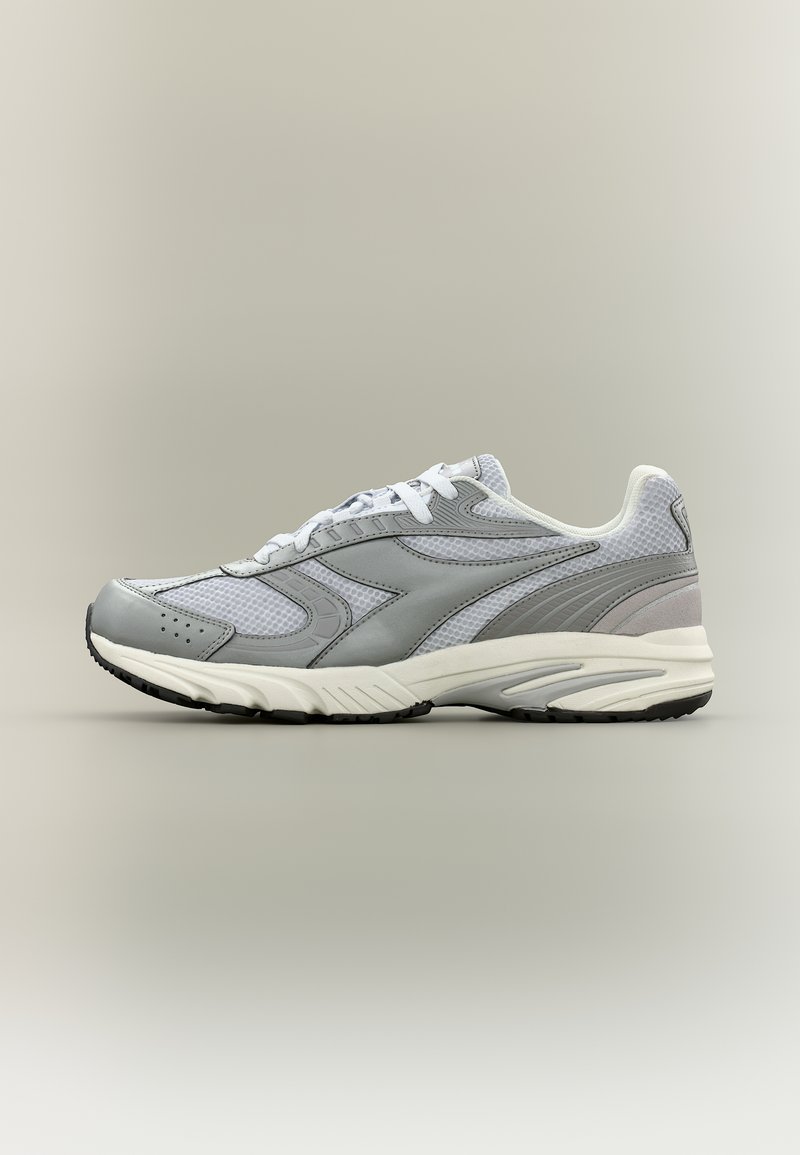 Αθλητικό παπούτσι ανοιχτού γκρι και λευκού χρώματος με επάνω μέρος από δίχτυ, κλείσιμο με κορδόνια και μαύρη σόλα, εμφανιζόμενο από το πλάι σε ουδέτερο φόντο.