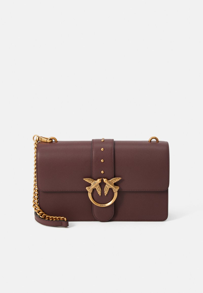 Rjava usnjena torbica z okrasjem v zlati barvi v obliki ptice, okroglo kovinsko podrobnostjo in verižnim ročajem. Gladka tekstura z bleščečimi poudarki.