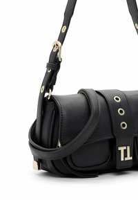 Sac à épaule en cuir noir avec bandoulière réglable, boucle dorée et œillets, et rabat avant avec fermoir métallique portant le logo "TI".