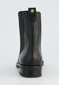 Bottines en cuir noir avec des côtés élastiques, bout arrondi et un petit talon empilé. Présente un petit logo doré sur l'arrière.