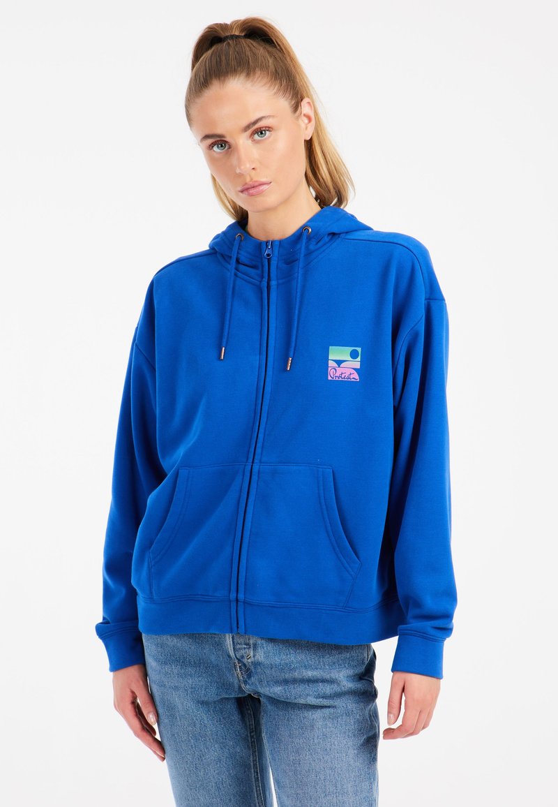 Sudadera azul con cremallera en material suave y bolsillo frontal. Presenta un colorido logo gráfico en el pecho y capucha con cordón.