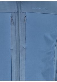 Helle blaue Jacke mit einem durchgehenden Reißverschluss, strukturiertem Oberpaneel und aufgenähtem Markenlogo entlang der Schulternaht. Glattes Material.