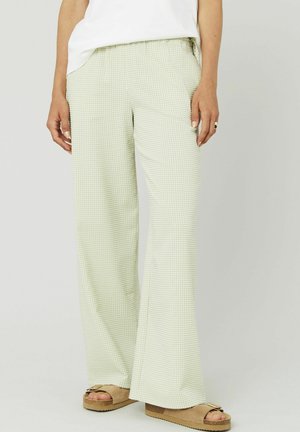 Pantalons à larges jambes en vichy vert clair avec une taille élastique. Tissu doux ; stylisés avec des sandales plates beige.