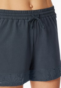 Donkergrijze katoenen shorts met een elastische tailleband en trekkoord, met bloemendecoratie aan de zoom. Zachte, lichte textuur.
