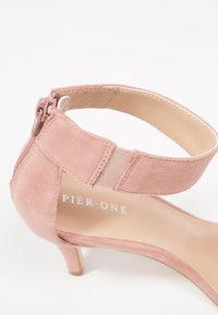 Sandale à talon haut en daim rose avec bride à la cheville, fermeture éclair au dos et détail élastique, étiquetée Pier One.