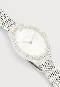 Ασημένιο ρολόι χειρός με στεφάνη, δείκτες καντράν και μπρασελέ διακοσμημένα με κρύσταλλα, δείχνει ώρα 8:10.