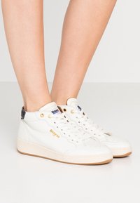 Hvide lædersneakers med perforeret tå, guldaccenter og mørkeblå hældetaljer. Har et høj-top design og gummisål.