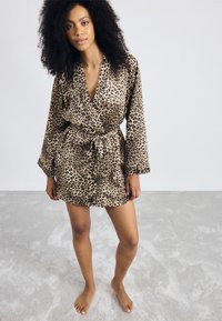 Leopárdmintás kimono köntös könnyű, sima anyagból; hosszú ujjakkal, átkötős előlappal és hozzáillő övvel tervezve.