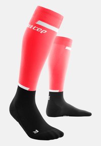 Calze a compressione rosse con sezione nera sul piede, caratterizzate da un design testurizzato e accenti bianchi sulla parte superiore e sul tallone.