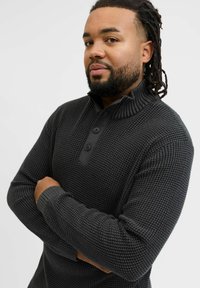 Dark gray knit pullover with a half-zip collar, ribbed accents, and three-button placket. Textured fabric and fitted sleeves.
