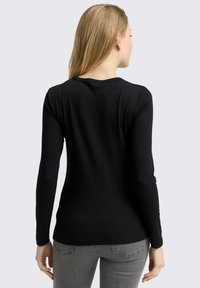 Schwarzes, langärmeliges, geripptes Shirt mit Rundhalsausschnitt, glatter Textur und taillierter Silhouette. Subtile Nahtdetails an den Schultern.