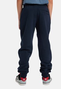 Marineblaue Sweatpants mit einem elastischen Bund und schmal zulaufenden Knöcheln. Verfügt über eine Gesäßtasche und ein weiches, strukturiertes Material.