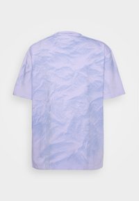T-shirt a maniche corte in lavanda chiaro con texture stropicciata. Design semplice con collo rotondo senza pattern o dettagli aggiuntivi.